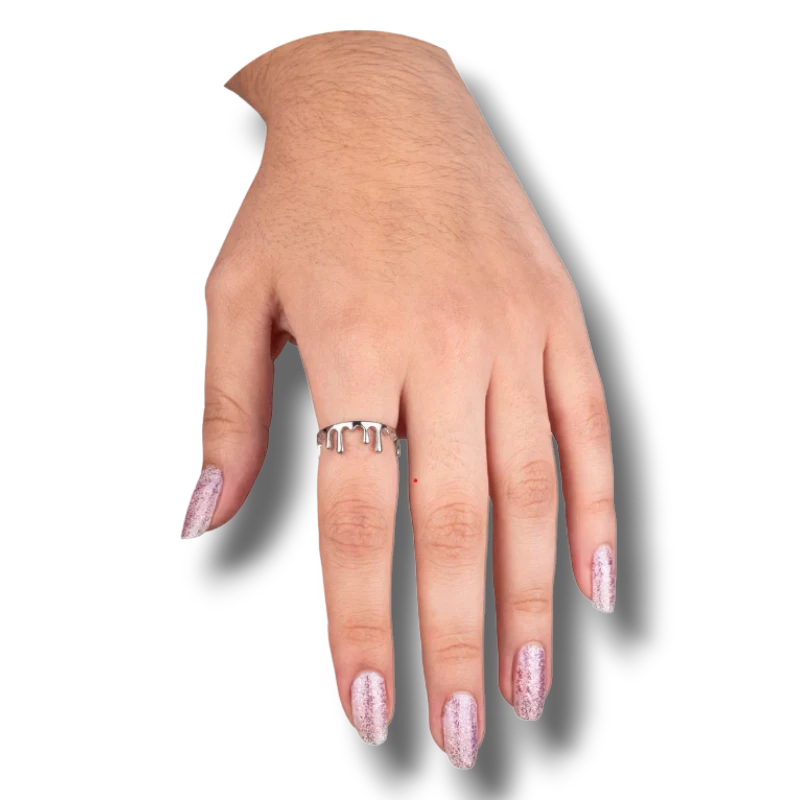 Anillo plateado con diseño de gotas de sangre de PartyStore puesto en el dedo de una mano con uñas brillantes