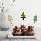 Tres cupcakes de chocolate decorados con palillos PartyStore en forma de árbol de Navidad con acabados brillantes