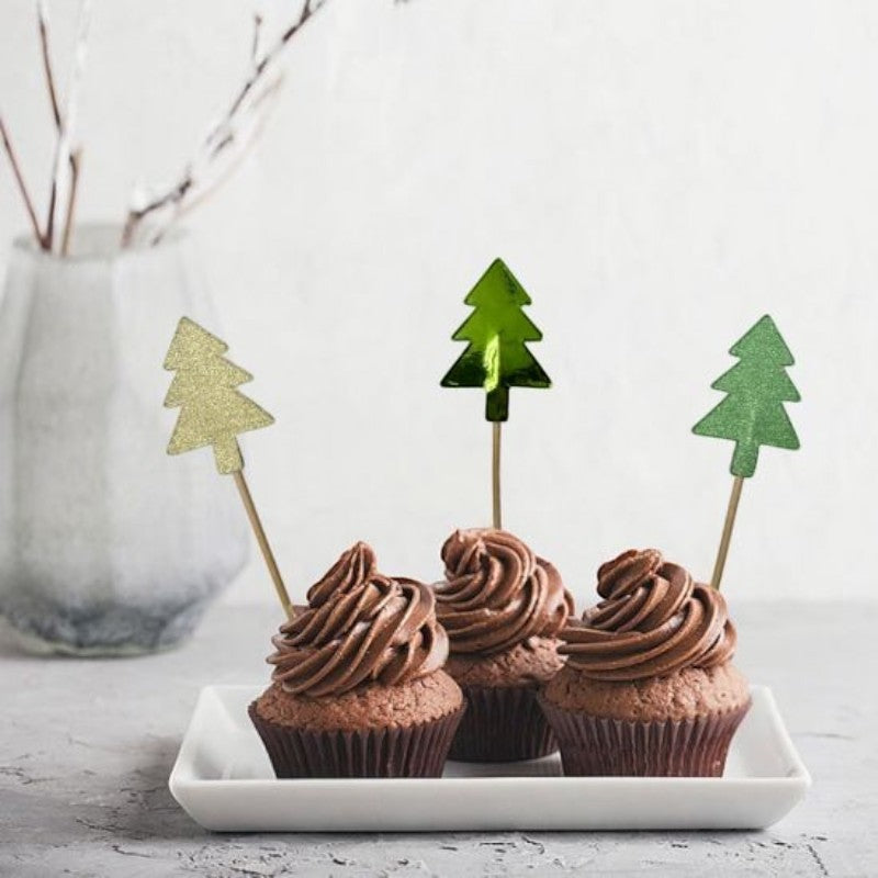 Tres cupcakes de chocolate decorados con palillos PartyStore en forma de árbol de Navidad con acabados brillantes